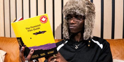 A smug looking man reads a book on feminism.