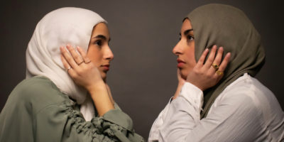 An image of two individuals wearing Hijab and facing each other