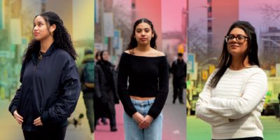 Three women standing in front of a dynamic colourful background.