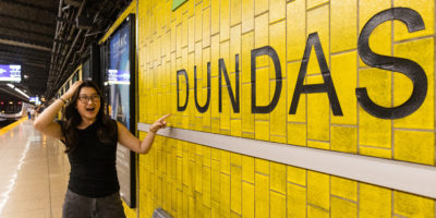 An individual exclaiming while pointing at the Dundas station sign on the platform.