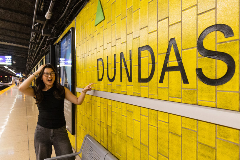 An individual exclaiming while pointing at the Dundas station sign on the platform.