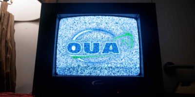 An image of an old television with a blue and grainy OUA logo on it.