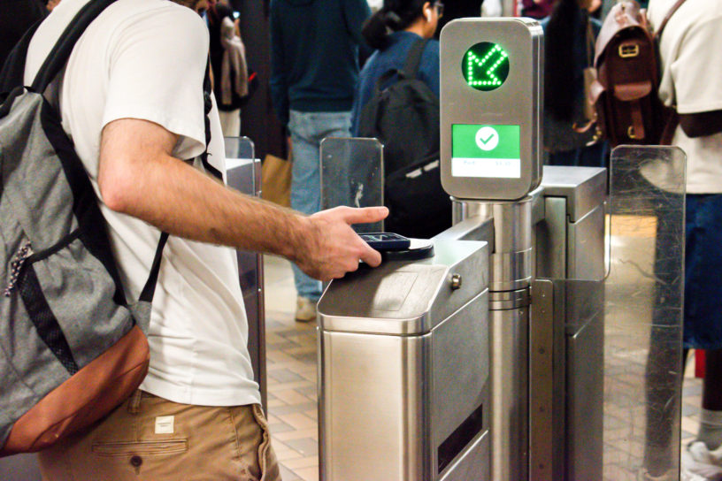 A student taps their phone at the TTC gates.