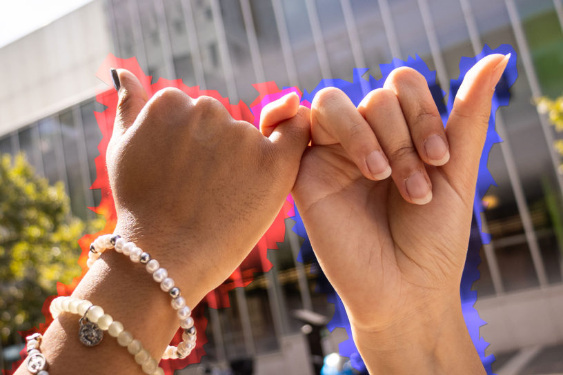 photo of two hands linking pinky fingers, with red colouring bordering one hand, and blue colouring bordering the other hand.