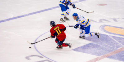 A Queen's player with the puck avoids his opponents