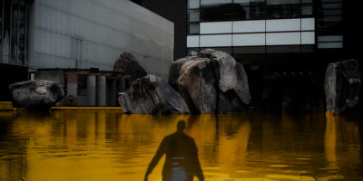 An photo illustration of a shadow of a person over a yellow coloured Lake Devo.