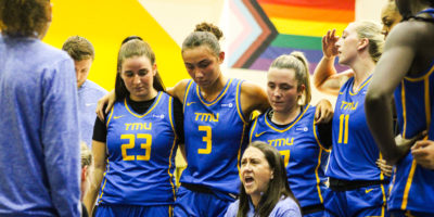 The TMU Bold women's basketball team huddles around head coach Carly Clarke