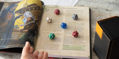 Image of a book on a table with five coloured dice laid out on the book.