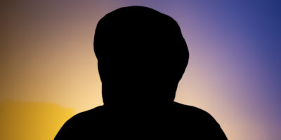 Image of a person's silhouette in front of a blue and yellow hue background.