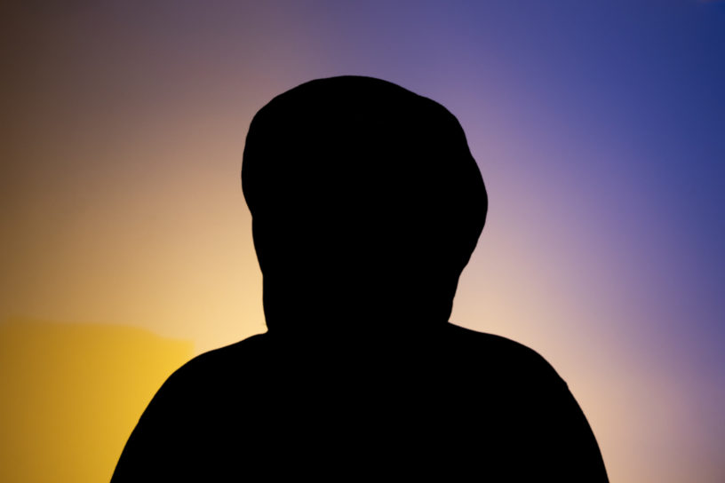 Image of a person's silhouette in front of a blue and yellow hue background.