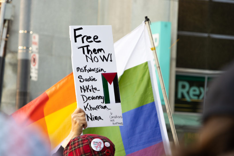 A protester holds a sign listing the names of the detained Freedom Flotilla Coalition members.