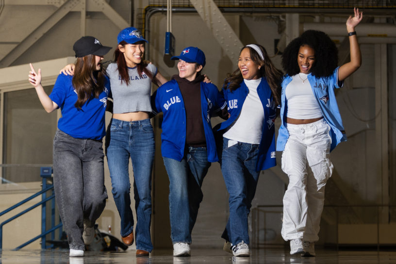 Image of five people walking down a hallway. They are all smiling and looking at each other.