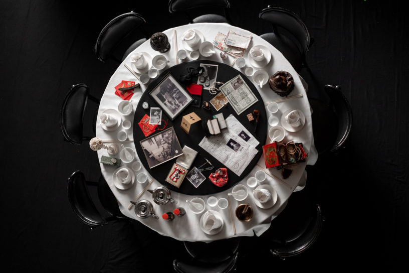 Image of a circular table with white bowls, plates and cups surrounding papers, picture frames and smaller items in the middle.
