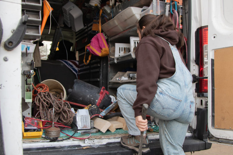 Image of a person holding a hammer and while walking into a truck filled with construction tools.
