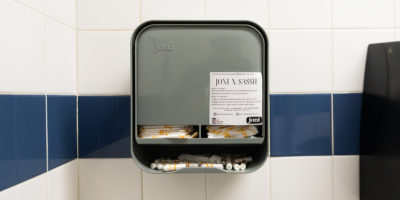 Image of a menstrual product dispenser that is mounted on a tile wall.