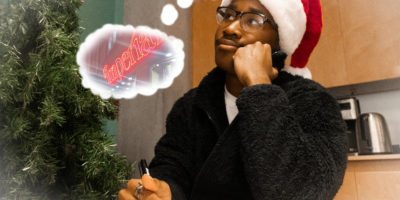 Image of a person sitting at a desk writing on a piece of paper with a though bubble illustrated around them. The thought bubble has a photo with a sign that reds "Imperial."