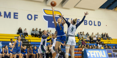 A TMU player reaches for the basket amidst Nipissing defense