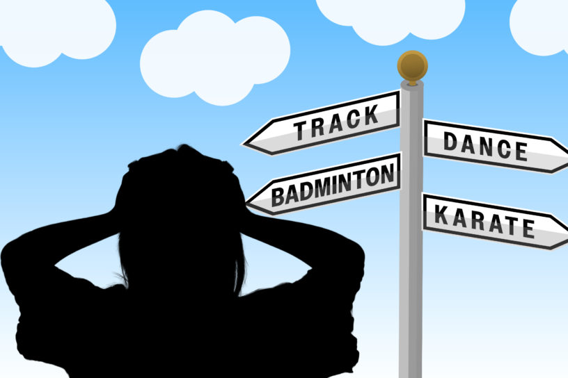 Person looking at a directional sign which reads "Track", "Dance", "Badminton" and "Karate".