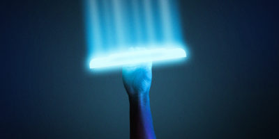 A arm is holding up a frisbee that is glowing blue against a dark background.