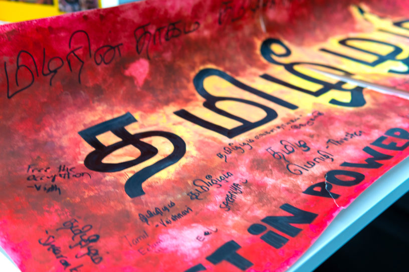 Image of a red and yellow painted poster with black text on it.