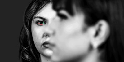 Black and white photo of two people, one facing the left and one facing forward with the colors of the Iranian flag in their eye