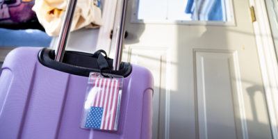 Image of a purple suitcase with an American flag attached to the tag.