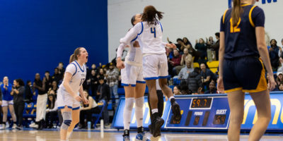 Two TMU players bump chests, celebrating a point
