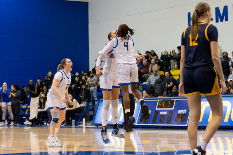 Two TMU players bump chests, celebrating a point