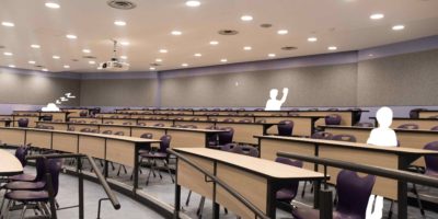 Photo of a empty lecture hall, with three white sketched figurines occupying three seats.