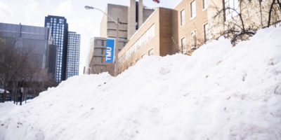 Photo of a snowbank with a banner that reads "TMU" in the background.