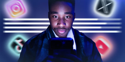 Image of a person facing forward looking at their phone screen with app logos spread out in the background.